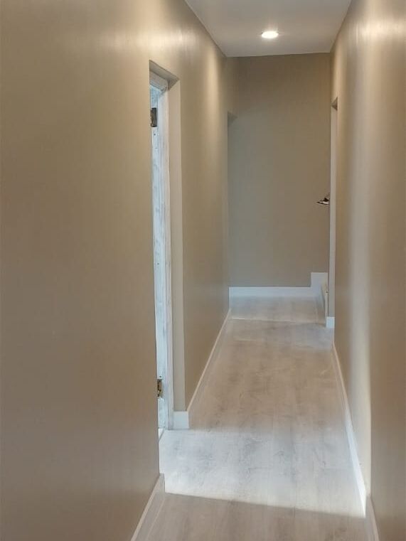 Freshly painted corridor with smooth beige walls, white skirting and downlights